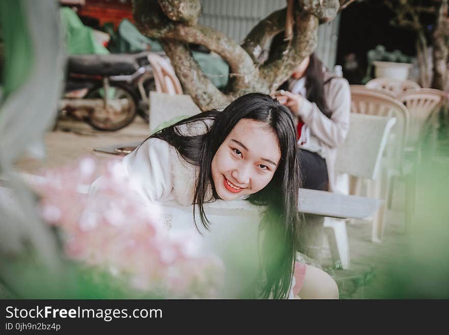 Selective Focus Photography of Woman Sitting on Chair Near Tree Branch