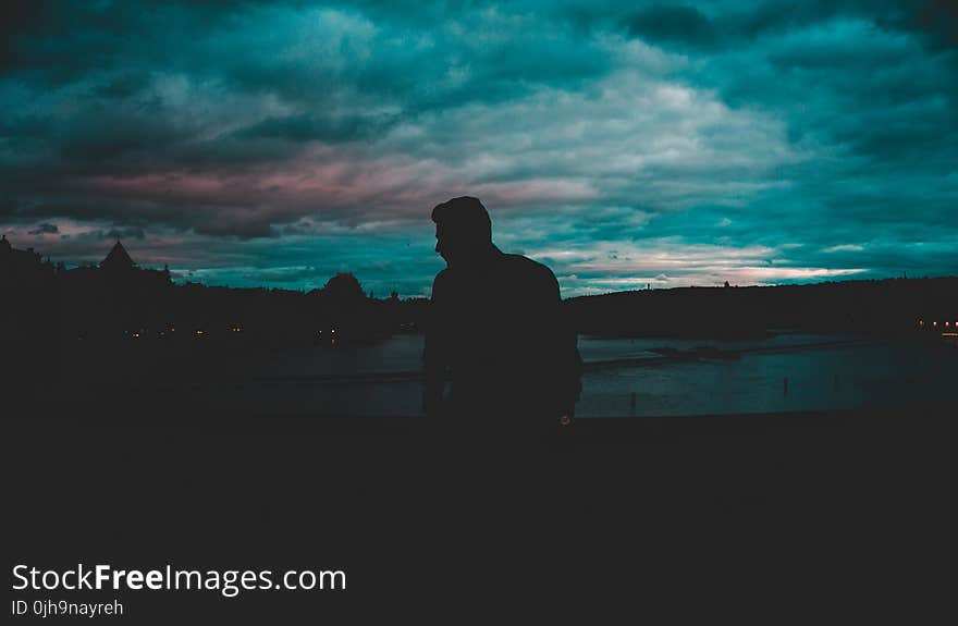 Man Silhouette Near Body of Water at Nighttime