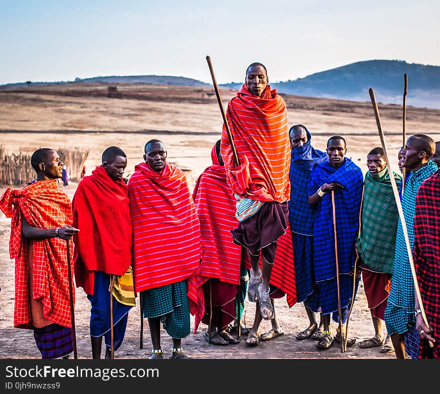 Photo of Group of Men Wearing Assorted Scarves Holding Sticks