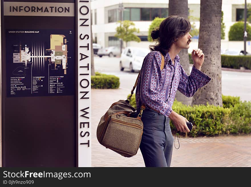 Person Wearing Purple Dress Shirt and Black Pants White Carrying Brown Sling Bag