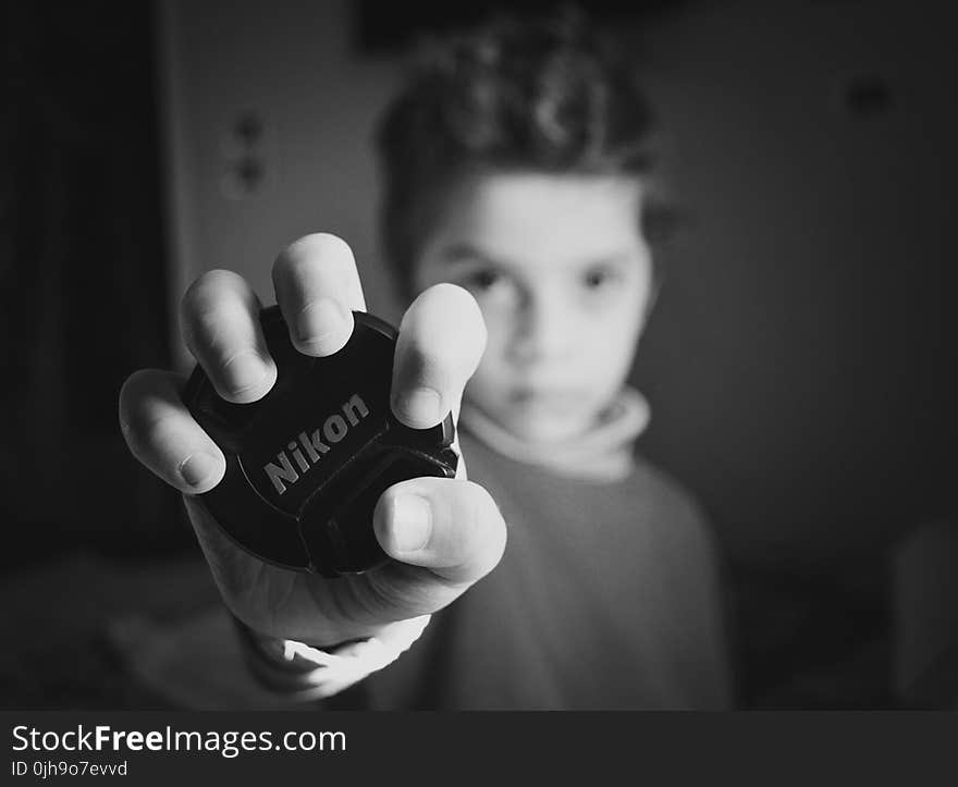 Selective Focus Photography of Boy Holding Nikon Lens Cover