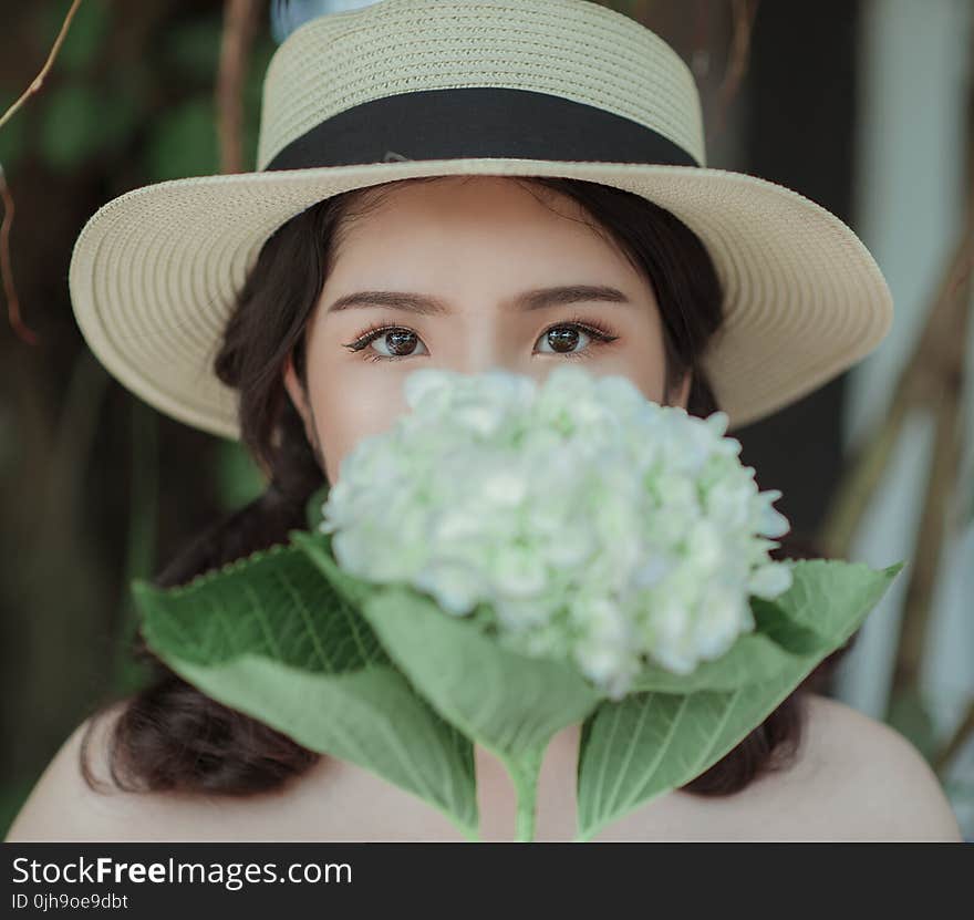 Woman Wearing White Hat Holding Flowers