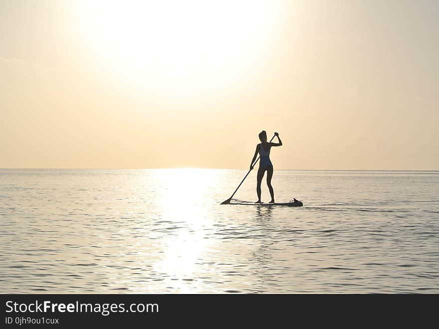 Woman Standing on Paddleboard on Body of Water