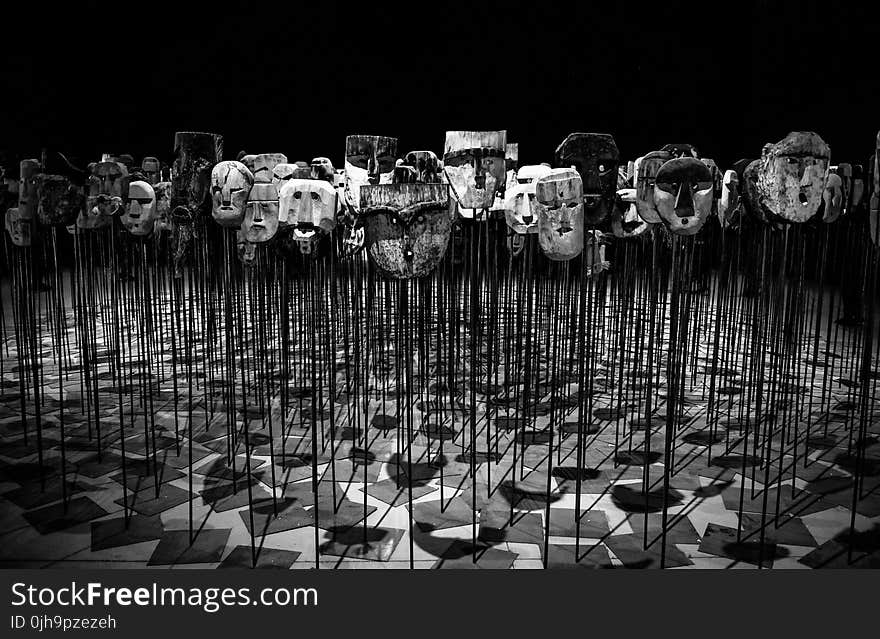 Greyscale Photo of Masks on a Stick