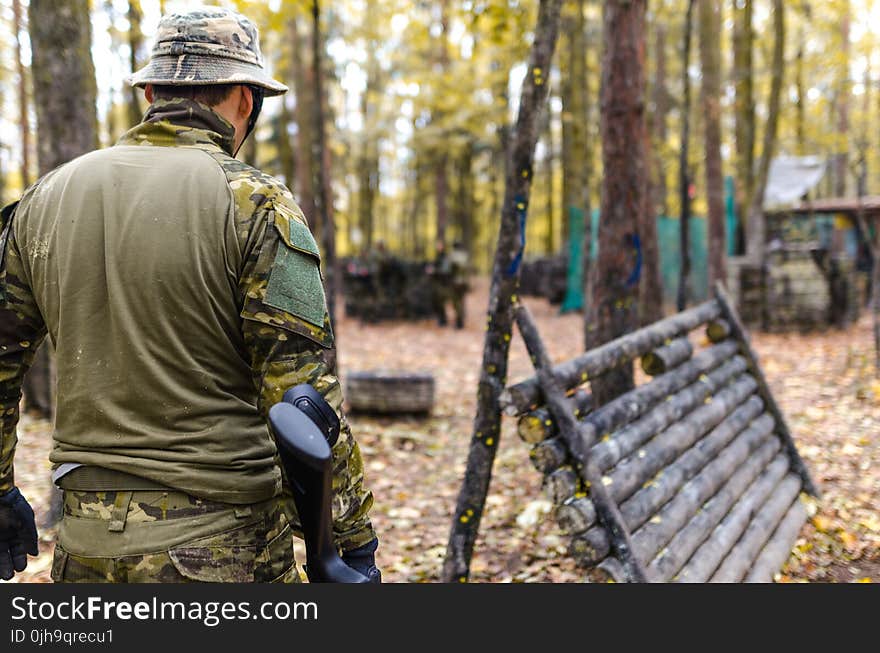 Selective Focus Photography of Man Wearing Camoflouge Suit While Holding a Gun