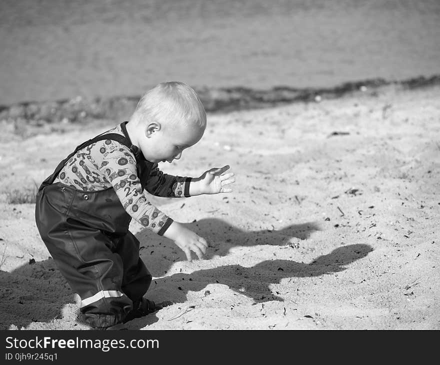 Grayscale Photography Of Toddler On Beach Sand