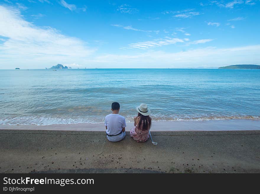 Man and Woman Sitting on Seashore