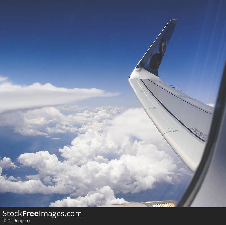 High-angle Photograph of Airplane Wings Above the Clouds Under Clear Blue Sky