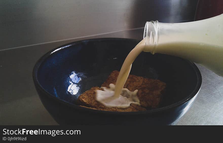Milk Being Poured in Blue Ceramic Bowl With Cookies