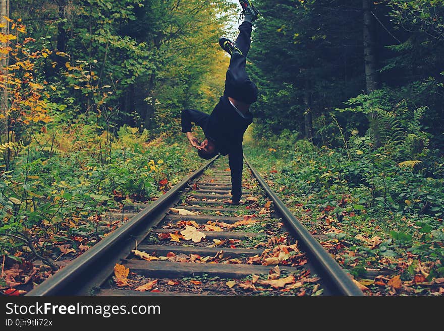 Man Standing With His Right Hand on the Train Rails in Middle of Forest