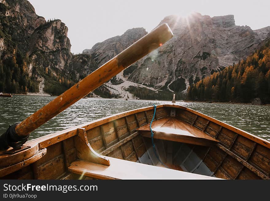 Brown Wooden Canoe on Body of Water Near Mountain