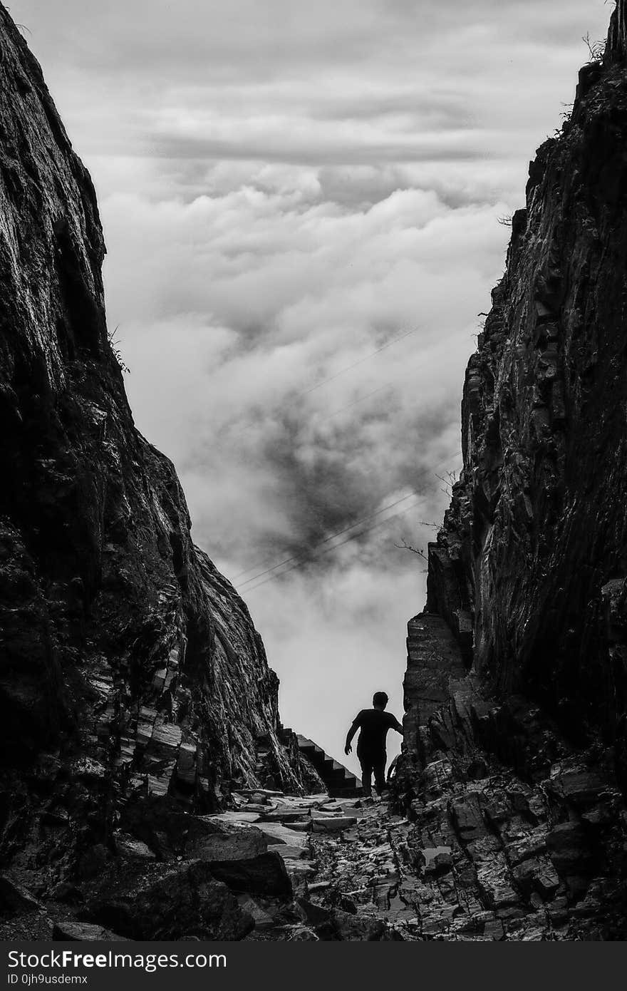 Silhouette of Man Walking Between Two Cliff