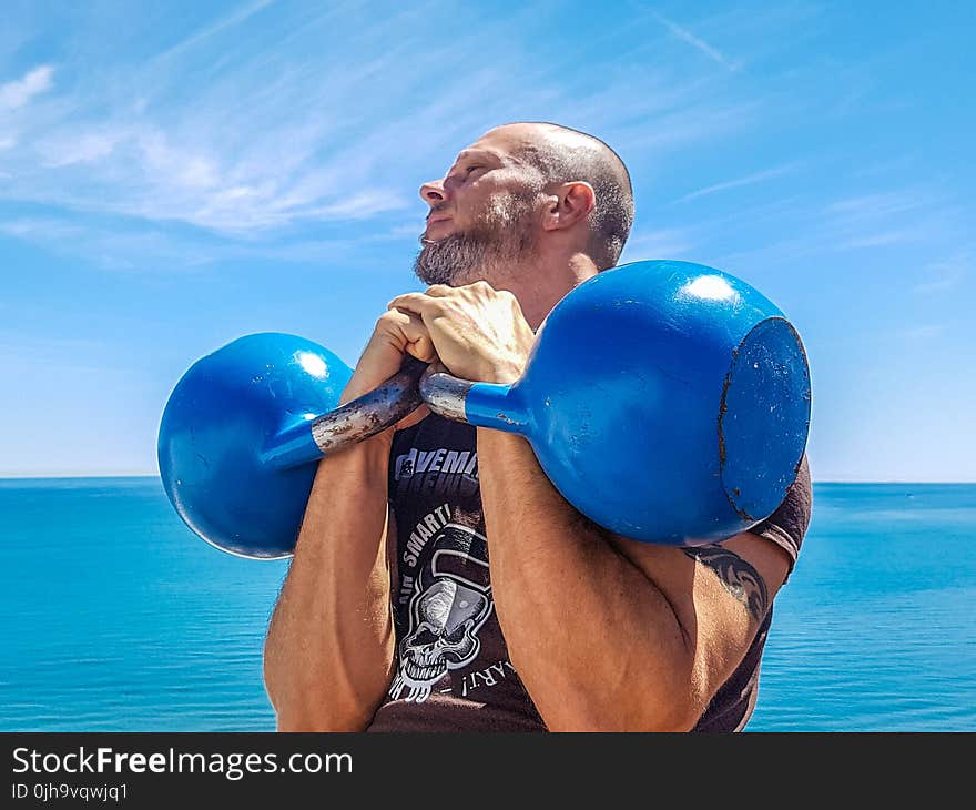 Man Lifting Pair of Blue Kettlebells