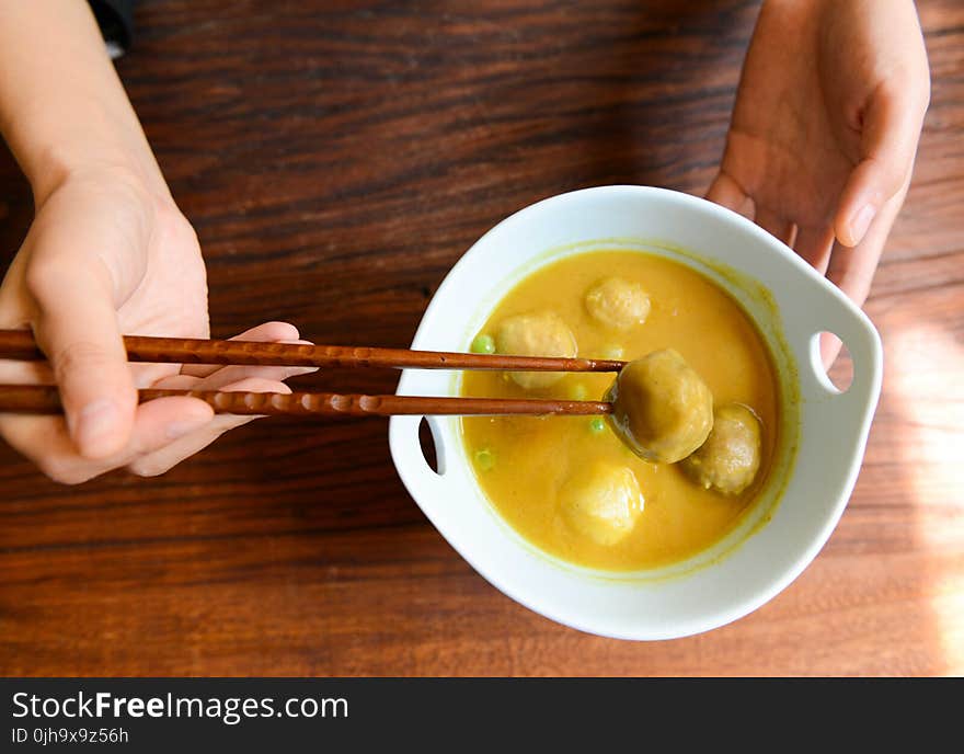 Person Holding Chopsticks and White Ceramic Bowl