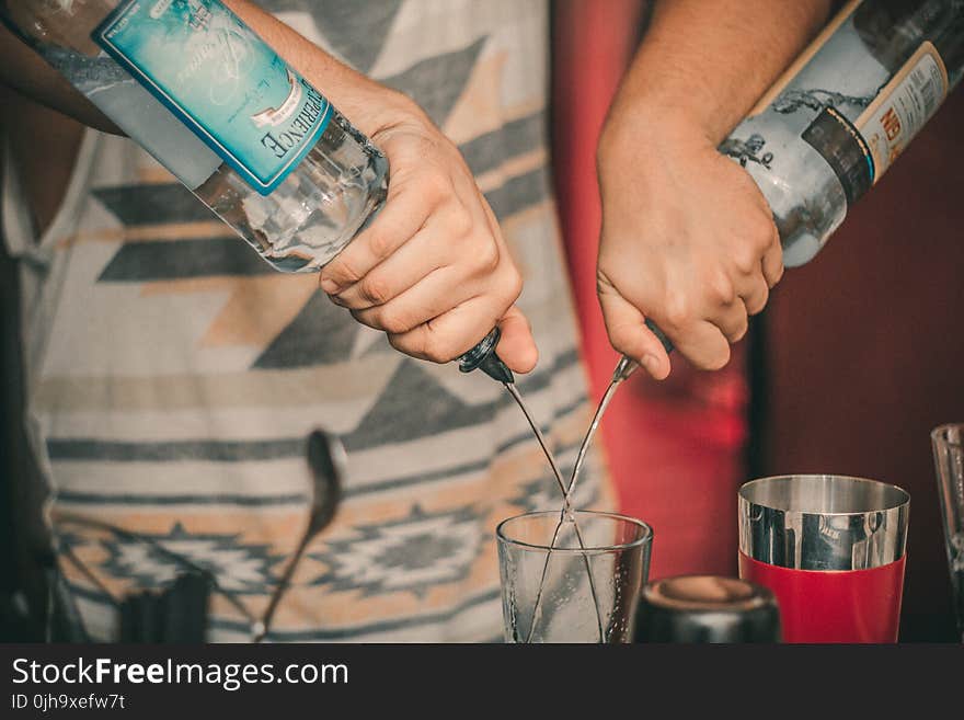 Person Holding Two Soda Bottles With Drinking Glass Below