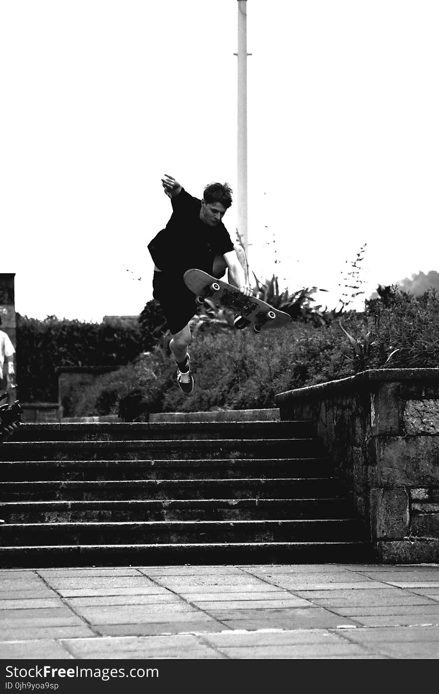 Grayscale Photo of Man Doing Trick on Skateboard on Park