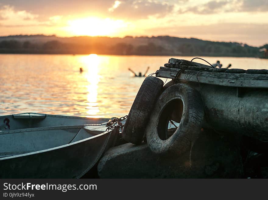 White Boat on Dock Near Two Auto Tires during Sunset