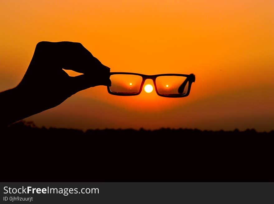 Silhouette of Person&#x27;s Hand Holding Eyeglasses during Golden Hour