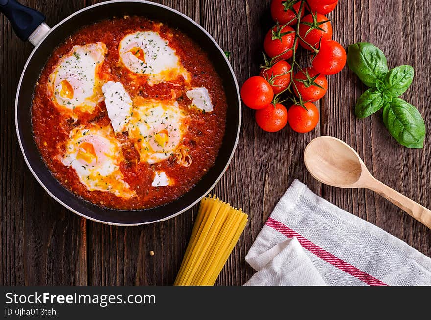 Black Frying Pan With Spaghetti Sauce Near Brown Wooden Ladle and Ripe Tomatoes