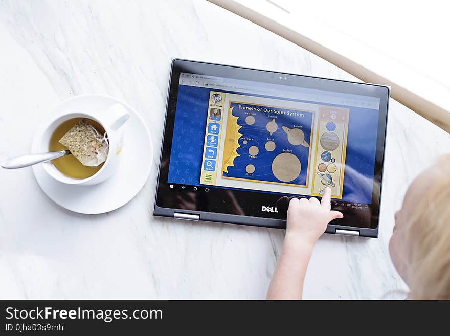 Kid Using Black Dell Tablet With Tea