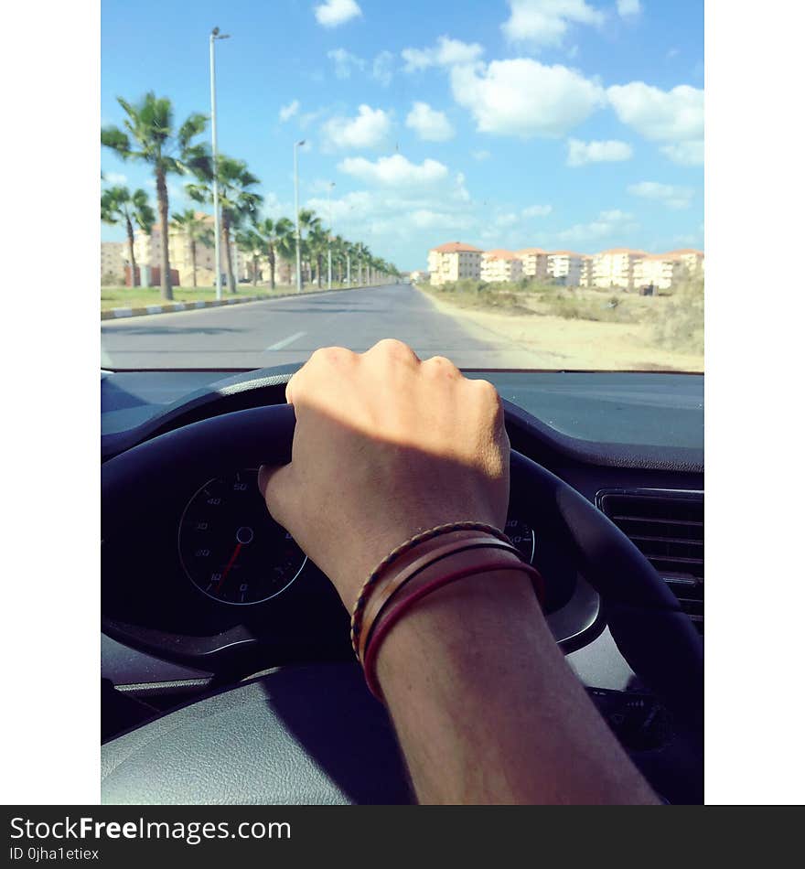 Person Withe Bracelets Holding Black Steering Wheel