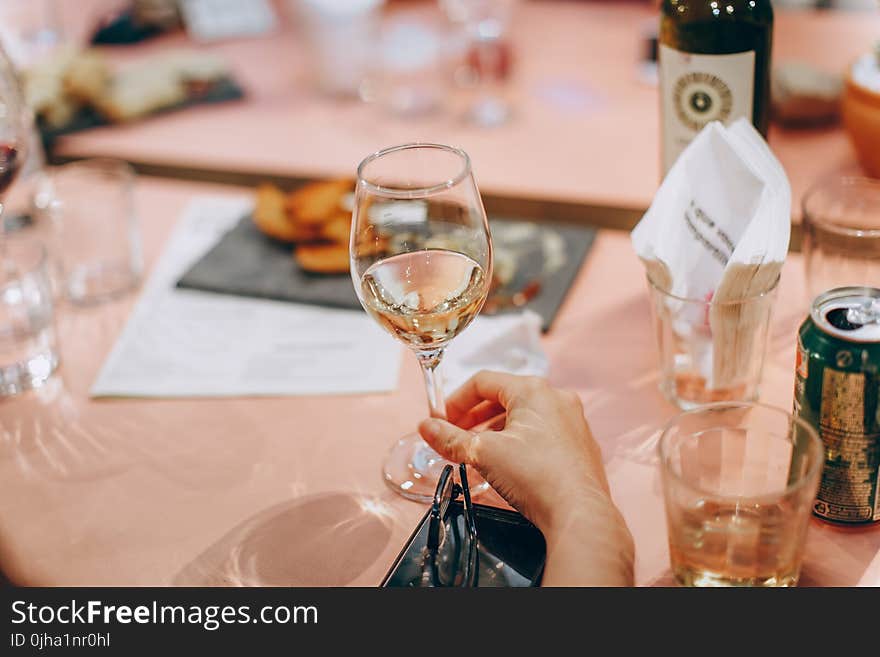 Person Holding Wine Glass Near Clear Shot Glasses