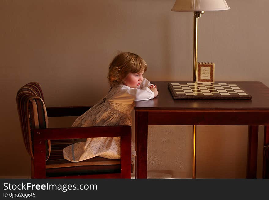 Child Setting on Chair in Front of Table