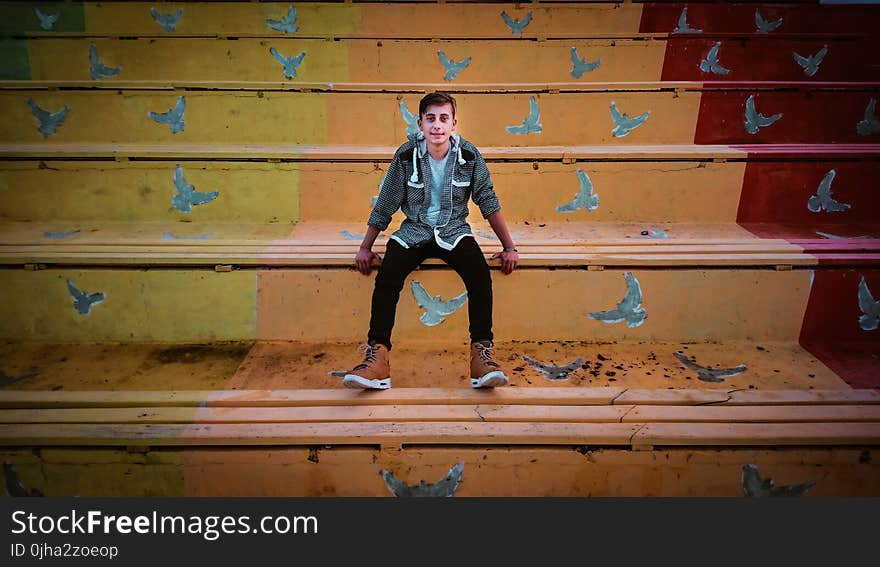 Man in Grey Zip-Up Hoodie And Black Fitted Jeans Sitting