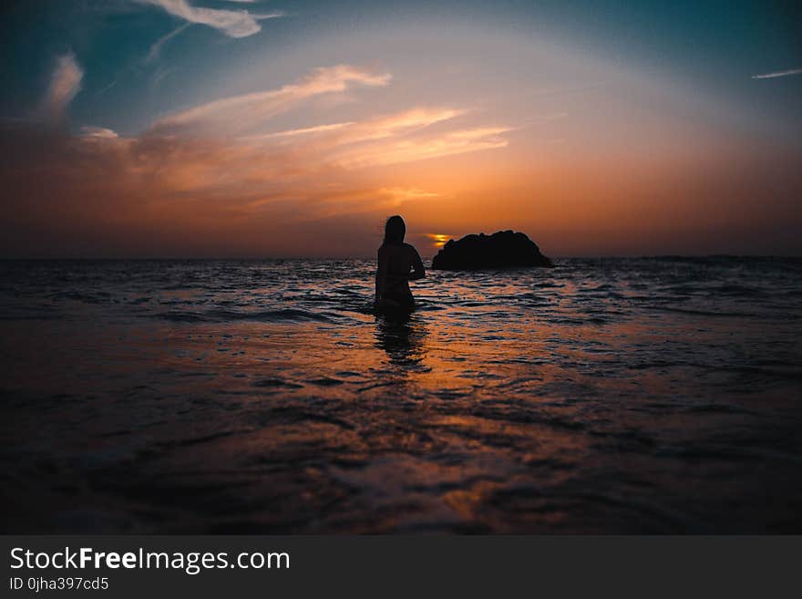 Silhouette of Woman On Ocean During Sunset