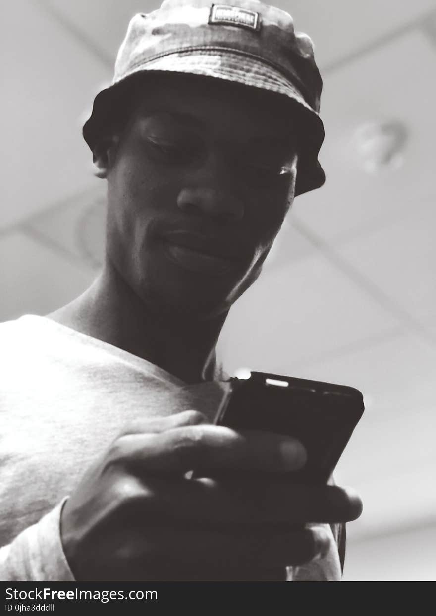 Man in Bucket Hat Holding Black Smartphone