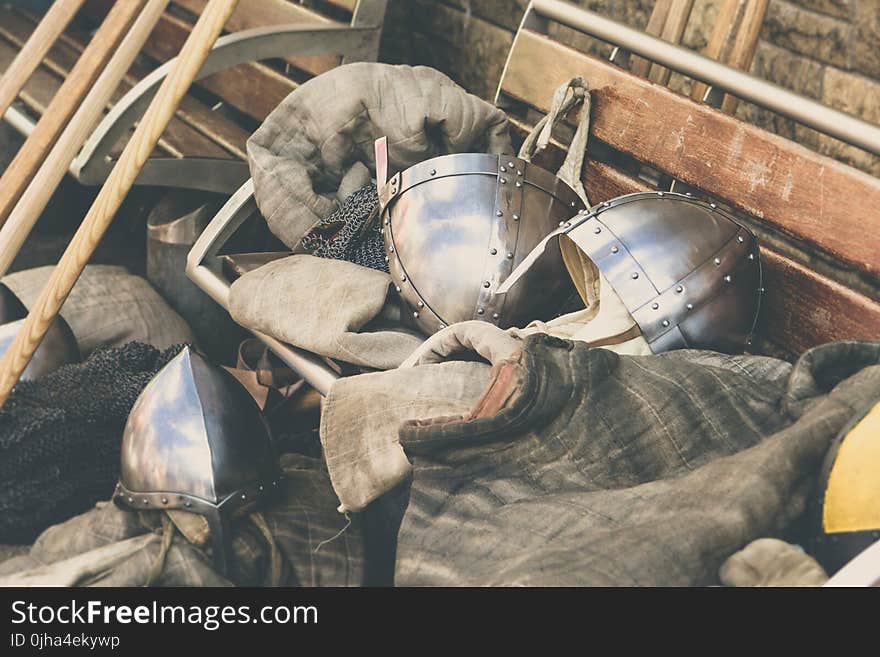 Two Gray Stainless Steel Soldier Helmet on Brown Wooden Bench