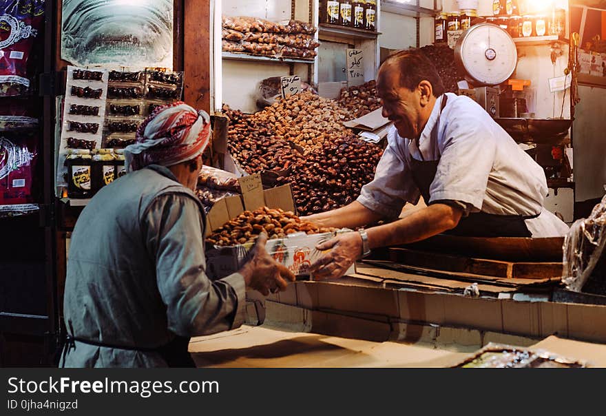 Man in Blue Top Giving Box to Man in Gray Top