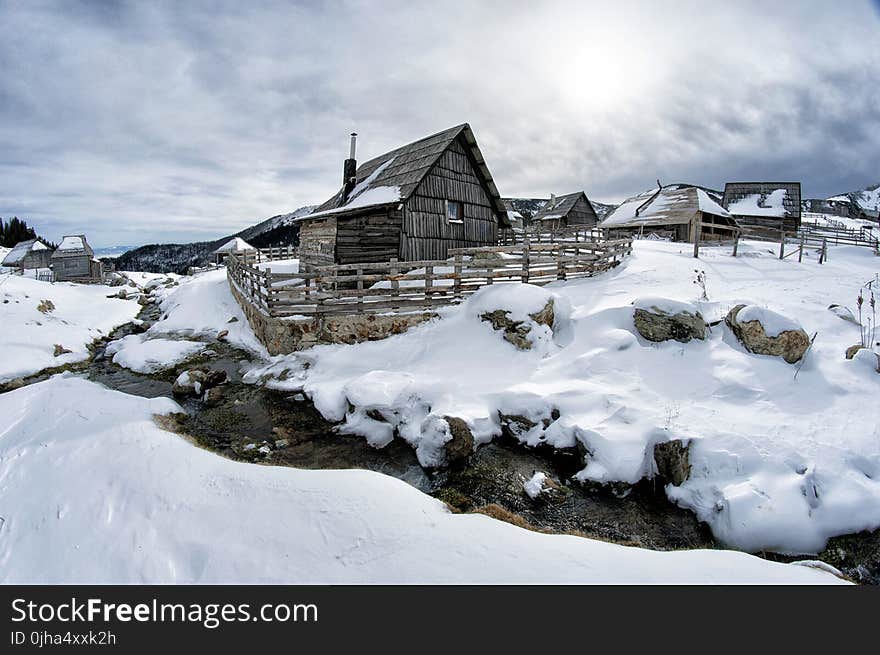 Black Wooden House Surrounded by Snow Under White Clouds