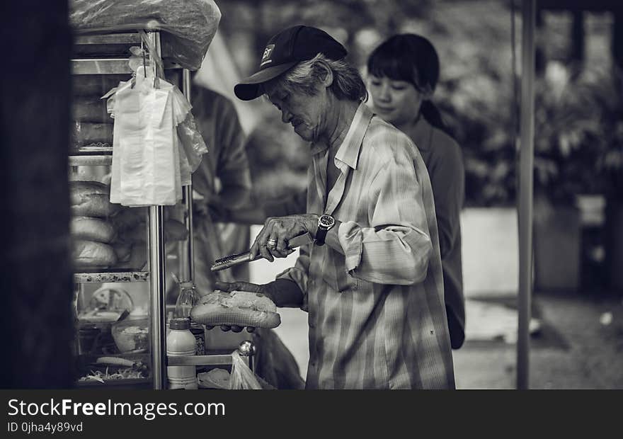 Man in Cap Holding a Pastry and Tong