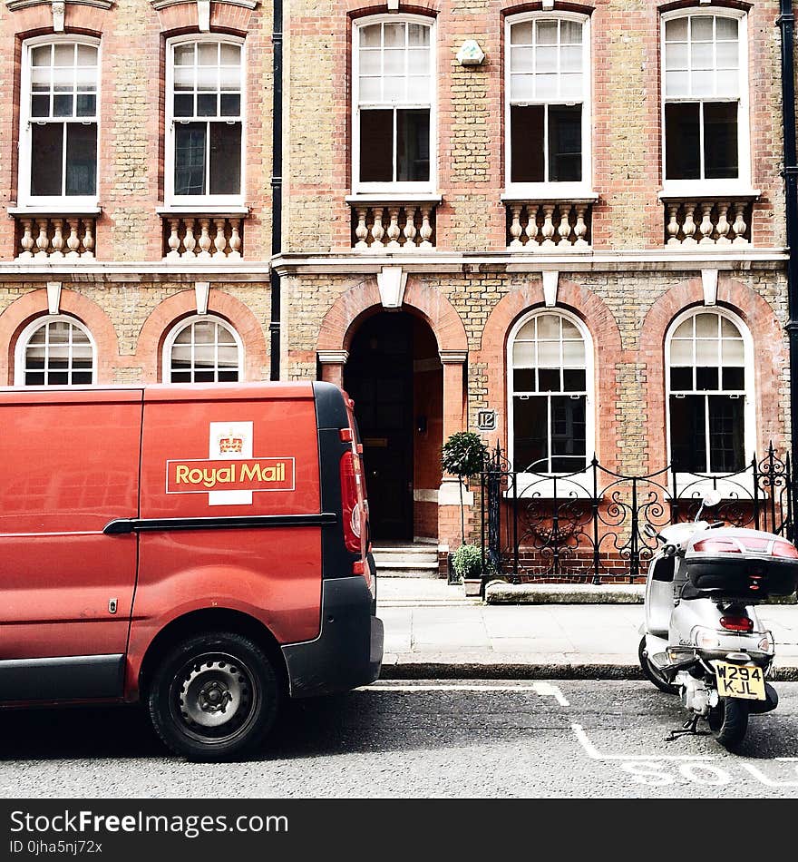 Red Royal Mail Parked Near Brown Brick Building