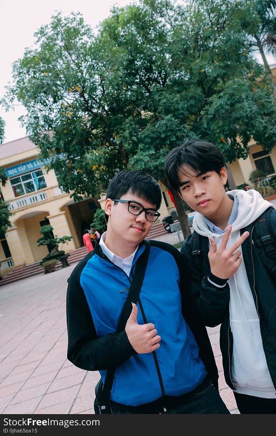 Man in Blue Hoodie Beside a Man in Black Jacket Standing Outdoors Under Blue and White Sunny Sky during Dayimte