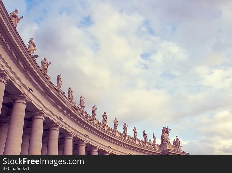 Gray Concrete Building With Human Statues Under Cloudy Sky