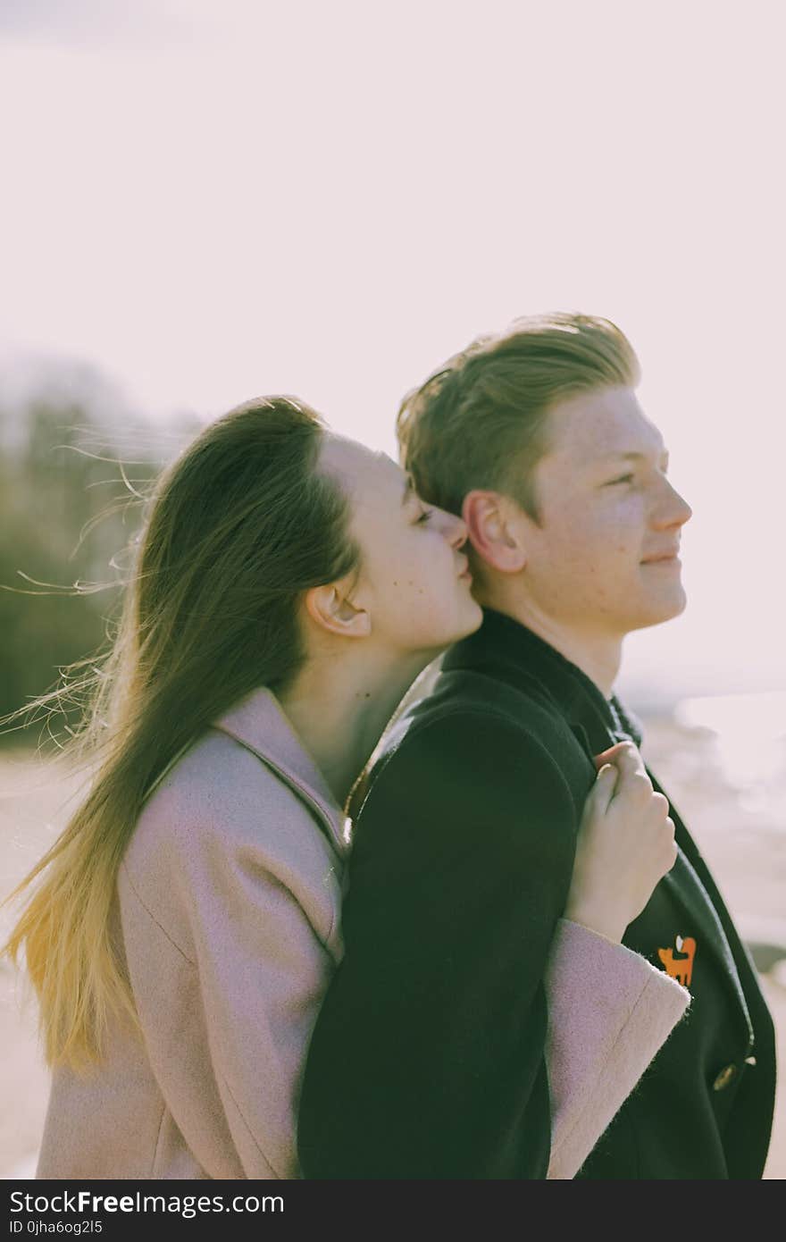 Woman Kissing the Back of Man&#x27;s Ear Near Sea