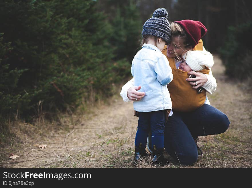 Woman With Brown Baby Carrier And Little Kid In White Jacket