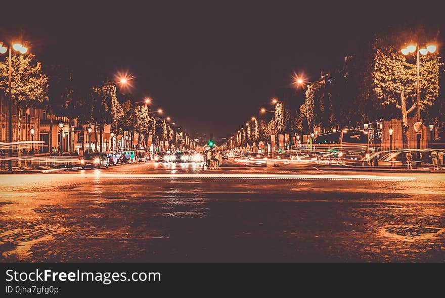 Lighted Street With Cars Passing by during Nighttime