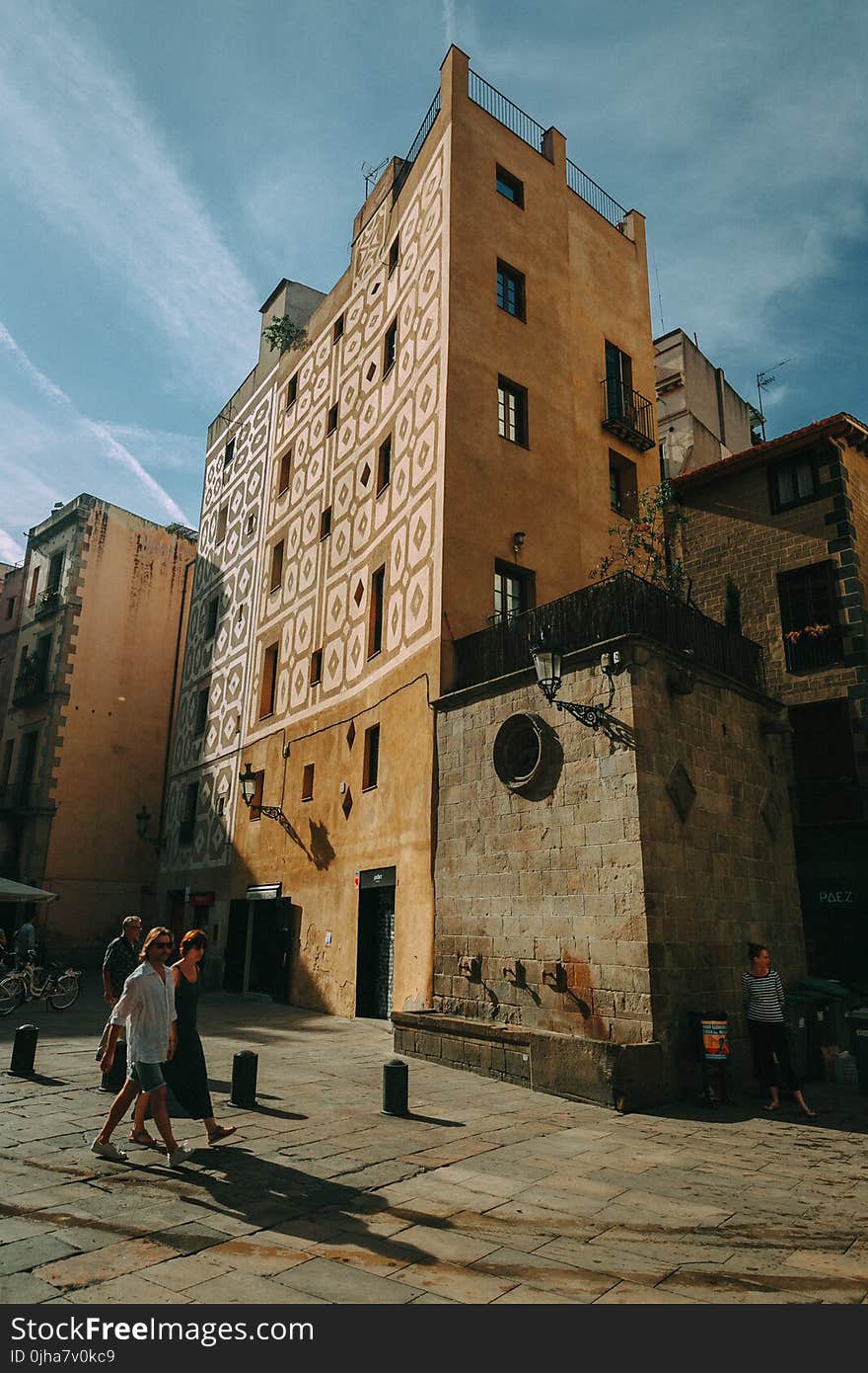 Man and Woman Walking Near Brown Concrete Building