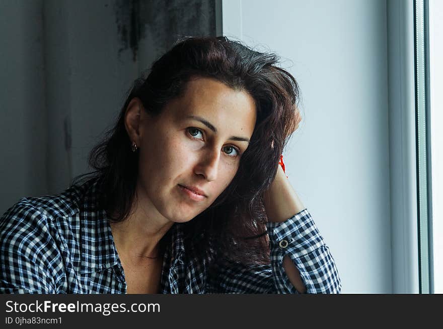 Woman in Black and White Gingham Long-sleeved Top Holding Her Hair Beside White Surface