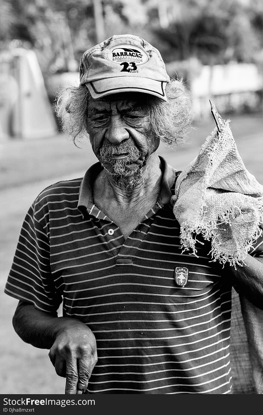 Grayscale Photography Of Man Wearing Polo Shirt And Holding Sack