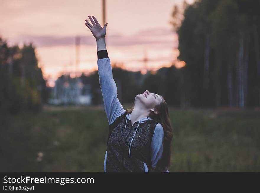 Woman in Gray and Black Zip-up Hoodie Raising Her Right Hand