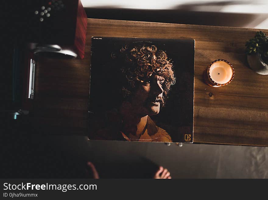 Man Wearing Brown Collared Shirt Photo on Brown Wooden Cabinet