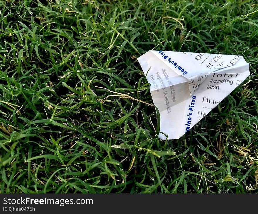 Receipt Folded Into Paper Plane on Grass