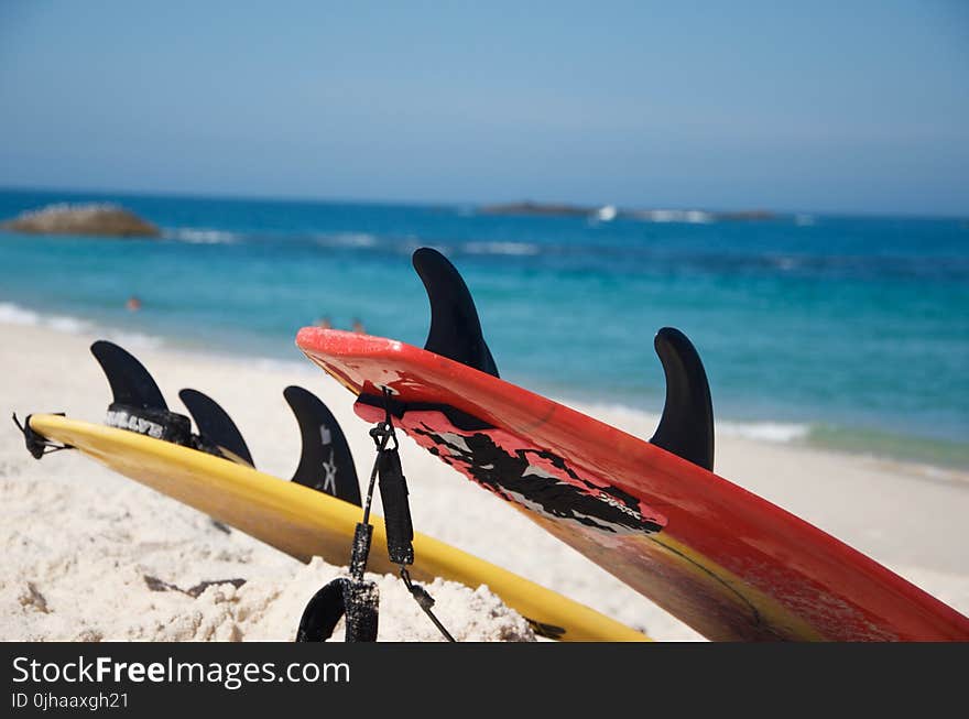 Yellow And Red Surfboards Near Blue Calm Body Of Water