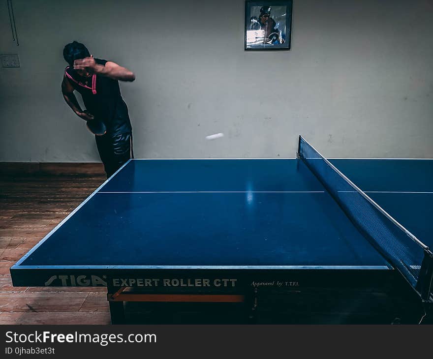 Man in Black Shirt Standing Near Blue Wooden Pingpong Table