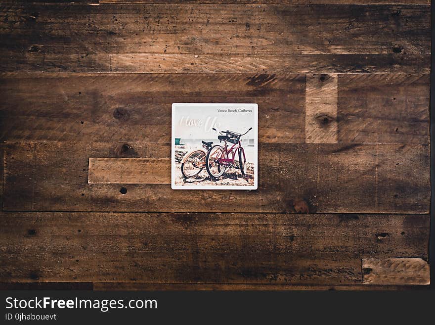 Two Assorted Bicycles Illustration on Brown Wooden Surface