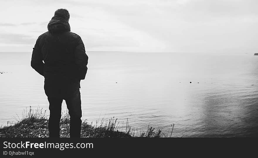 Silhouette of Man Standing Near Body of Water